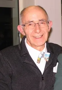 Carmelo Fedel saluta i libri della biblioteca di Baselga