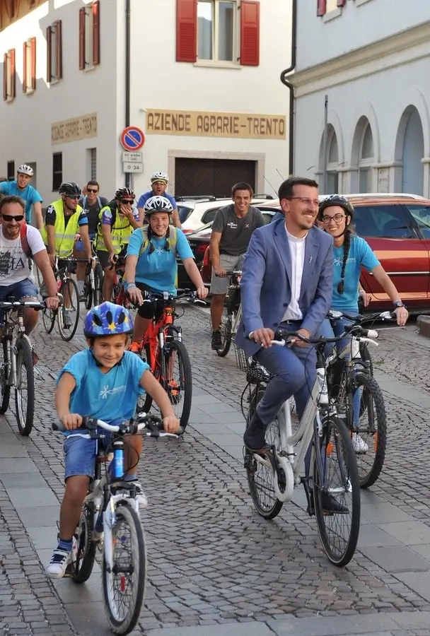 Don Daniele Armani arriva in bicicletta da Cles