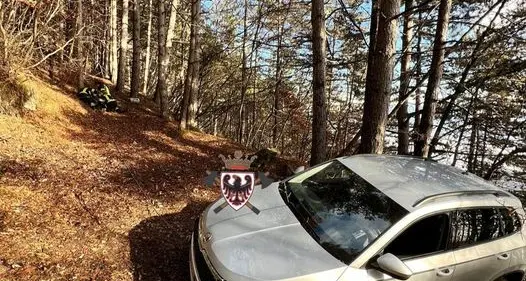 Auto scivola lungo una strada forestale a Fai della Paganella