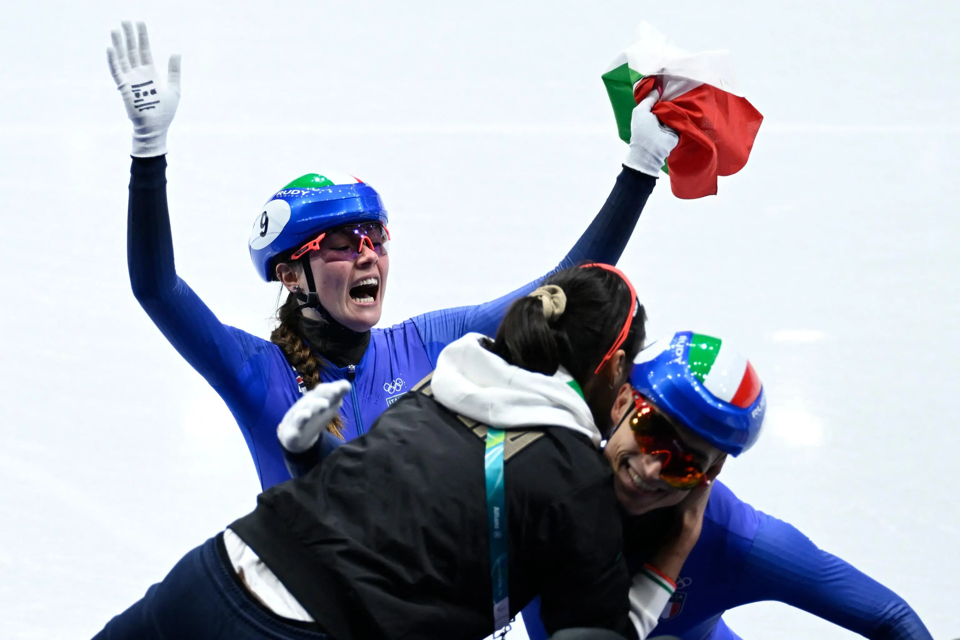 Team Italy's Elisa Confortola and Pietro Sighel celebrate with their coach Qi Mengyao after winning gold in the short track speed skating mixed team relay final during the Milano Cortina 2026 Winter Olympic Games at Milano Ice Skating Arena in Milan on February 10, 2026. (Photo by WANG Zhao / AFP)