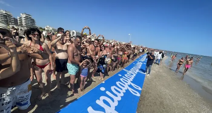 Ferragosto: flash mob con i piedi nell’acqua e le mani a cuore sulla spiaggia di Rimini